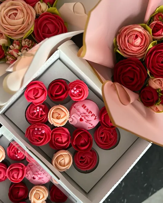 Kutija crvenih i ružičastih mafina pored buketa